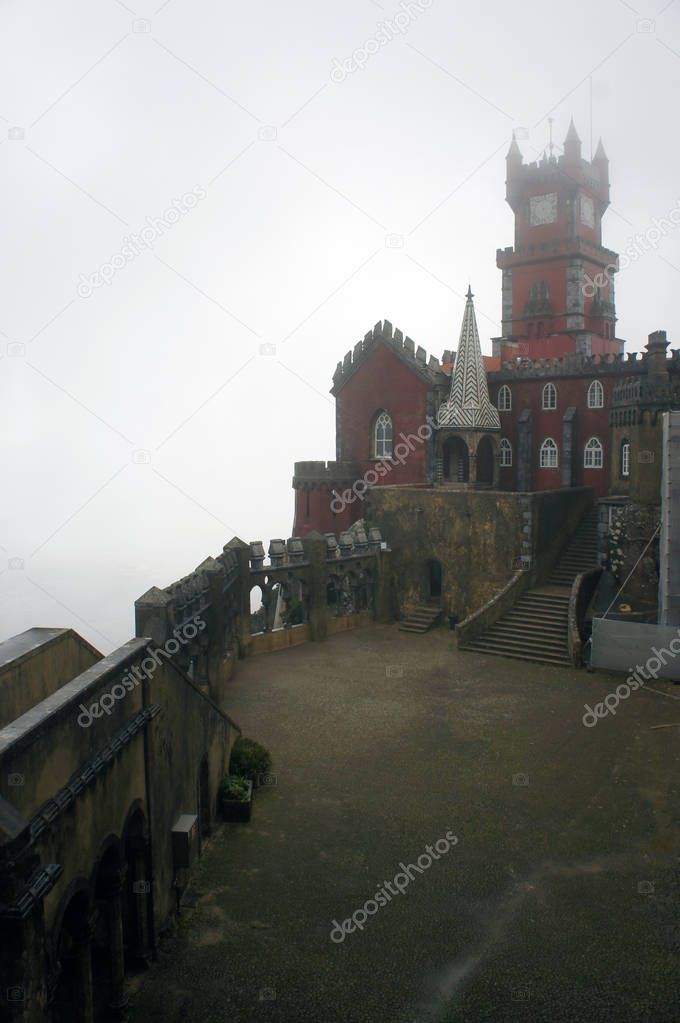 Red tower and patio of Da Pena palace during foggy, rainy weather, Sintra, Portugal