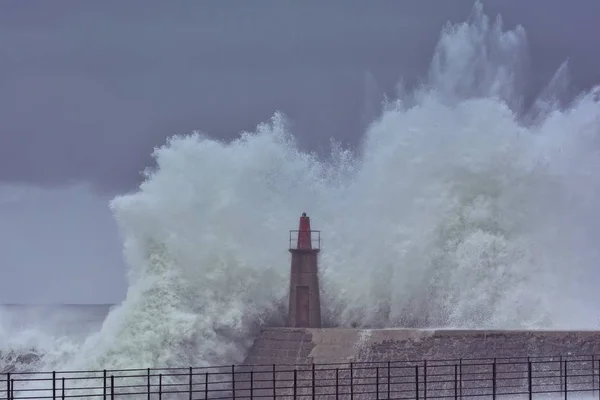 Stormy wave over old lighthouse and pier of Viavelez.