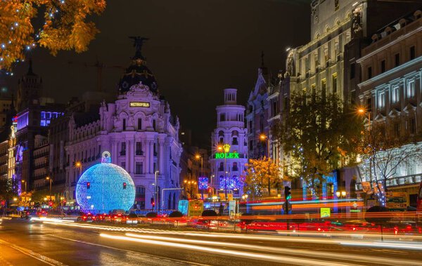 Madrid, Spain - November 30, 2019. Gran Via street at nightfall illuminated by christmas lights and a shinny christmas ball. View from Alcala street.