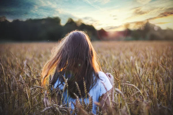 Jovem em um campo com orelhas ao pôr do sol — Fotografia de Stock