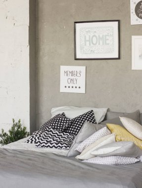 Çatı odasında yastıklar ile yatak. Beton duvarlar, posterler
