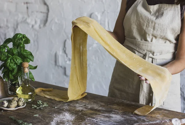 Young woman in apron holding dough for homemade pasta — Stock Photo, Image