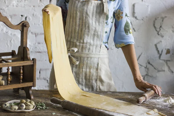 Young woman in apron holding dough for homemade pasta — Stock Photo, Image