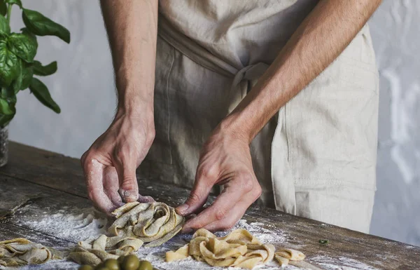 The young man in an apron preparing homemade pasta — Stock Photo, Image