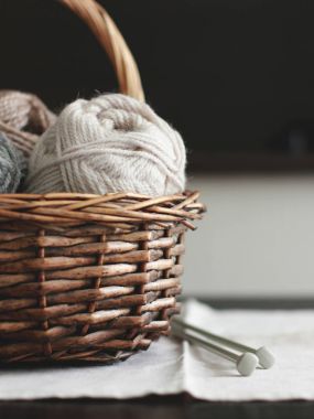 Bej renkli yün iplik örgü iğneleri ile kahverengi ahşap sepeti