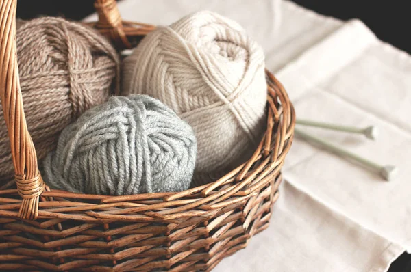 Ecru, bruin en grijs wol garen met naalden in houten mand — Stockfoto