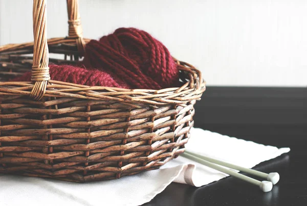 Wool burgundy yarn with needles in wooden basket — Stock Photo, Image