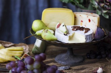 Metal tepsi, ahşap zemin üzerine taze meyve farklı peynir