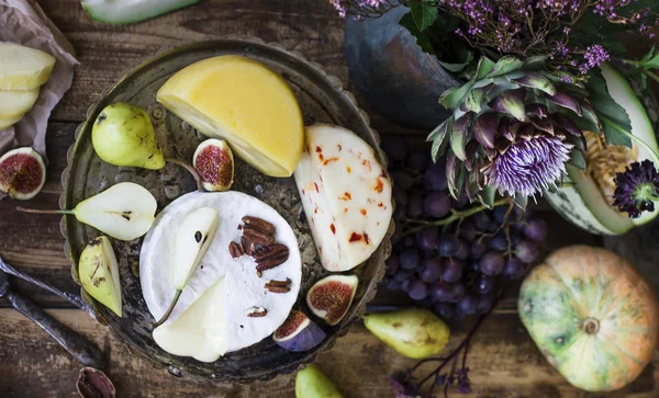 O queijo diferente, frutas frescas e flores de jardim em fundo de madeira — Fotografia de Stock