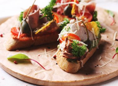 Jambon, otlar ve yuvarlak tahta üzerinde domates Bruschetta sandviç 