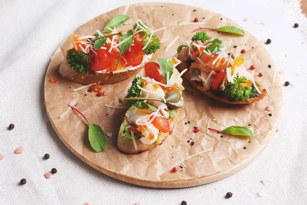 Sandwiches mit rotem Fisch, Tomaten, Mozzarella und Kräutern auf Rundholzbrett — Stockfoto