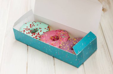 Kutusunda Beyaz ahşap arka plan üzerinde renkli donut
