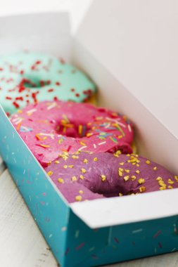 Beyaz ahşap arka plan kutusunda renkli donut