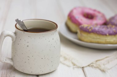 Fincan çay ve taze çörek ahşap arka plan üzerinde beyaz plaka