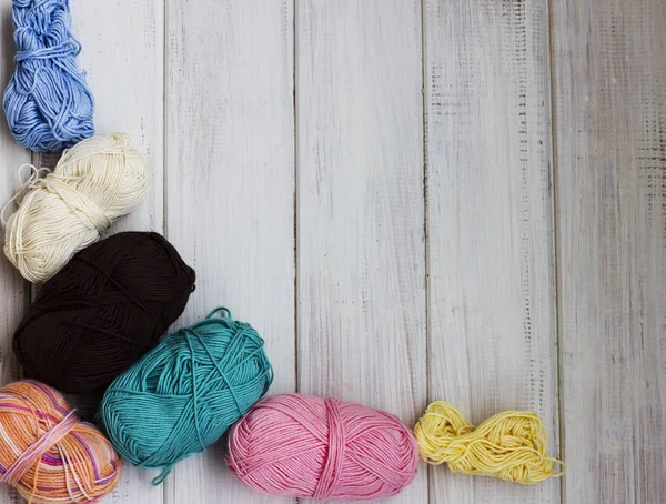 Colored cotton yarn on white wooden background. Copy space