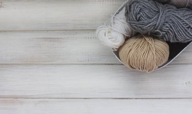 Beyaz ahşap zemin üzerinde bir sepet içinde yün iplik parlak renkler