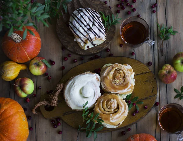 Fresh cinnamon rolls with tea, pumpkins and apples. View from to — Stock Photo, Image