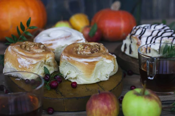 Fresh cinnamon rolls with tea, pumpkins and apples — Stock Photo, Image