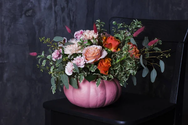 Autumn floral bouquet in pumpkin vase on black chair — Stock Photo, Image