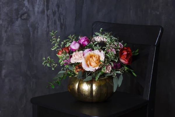 Autumn floral bouquet in pumpkin vase on black chair — Stock Photo, Image