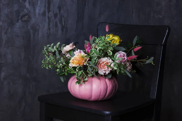 Autumn floral bouquet in pumpkin vase on black chair — Stock Photo, Image