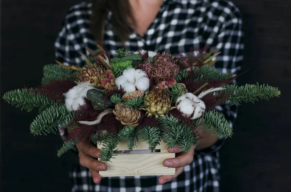 The composition of fir branches and cones in wooden box in the hands — Stock Photo, Image