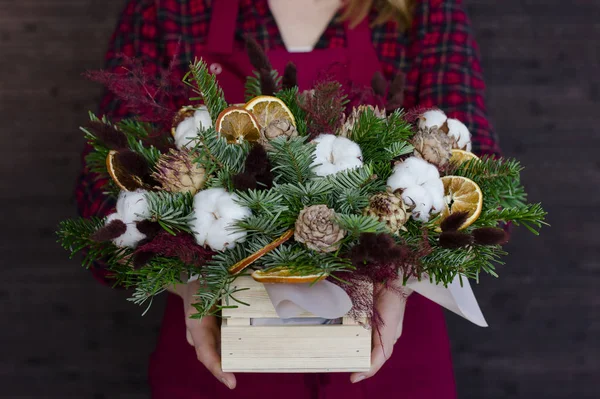 The composition of fir branches and cones in wooden box in the hands — Stock Photo, Image