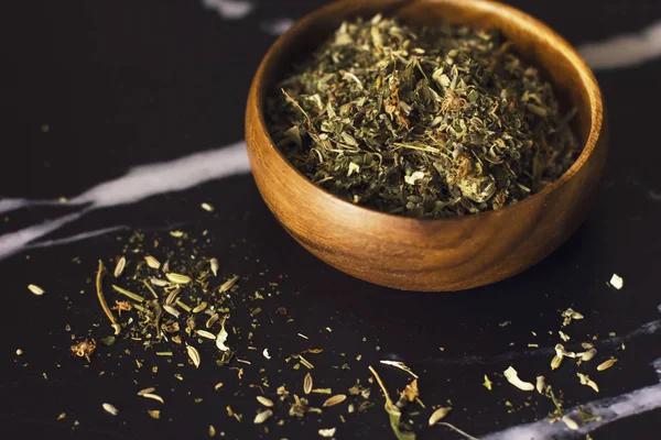 Травяной чай в деревянной чашке на черном мраморном фоне — стоковое фото