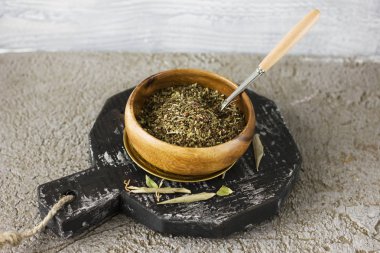 Gri zemin üzerine kaşıkla ahşap bir fincan kuru baharat