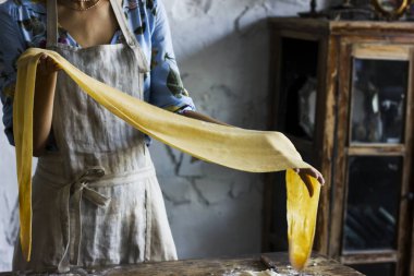 Genç kadın güzel elbise ve bir önlük için makarna hamur hazırlama