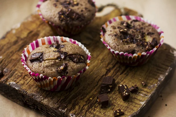 Muffins caseiros com chocolate em uma placa de madeira velha — Fotografia de Stock