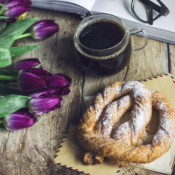 Bodegón con tulipanes, un libro, café y un pretzel sobre el fondo de madera viejo —  Fotos de Stock