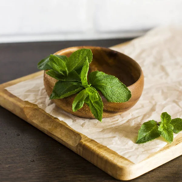 Leaves of fresh mint in a wooden bowl on the kitchen table — Stock Photo, Image