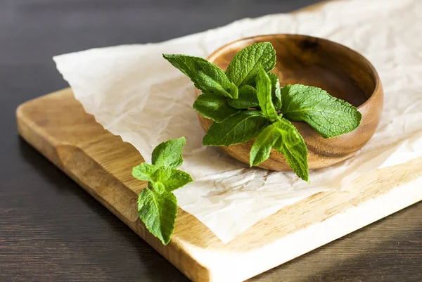 Leaves of fresh mint in a wooden bowl on the kitchen table — Stock Photo, Image