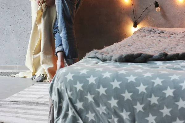 Спальня в стиле лофт, кровать с серым одеялом и мужчина и женщина на заднем плане — стоковое фото