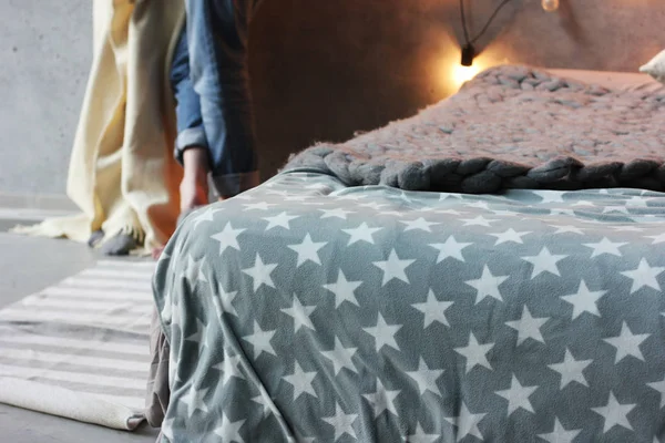 Спальня в стиле лофт, кровать с серым одеялом и мужчина и женщина на заднем плане — стоковое фото