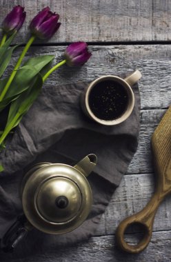 Bitki çayı, metal çaydanlık ve gri ahşap zemin üzerine lale ile natürmort