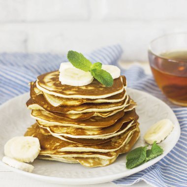 taze pişmiş krep muz beyaz tabak ve bardak çay ile 