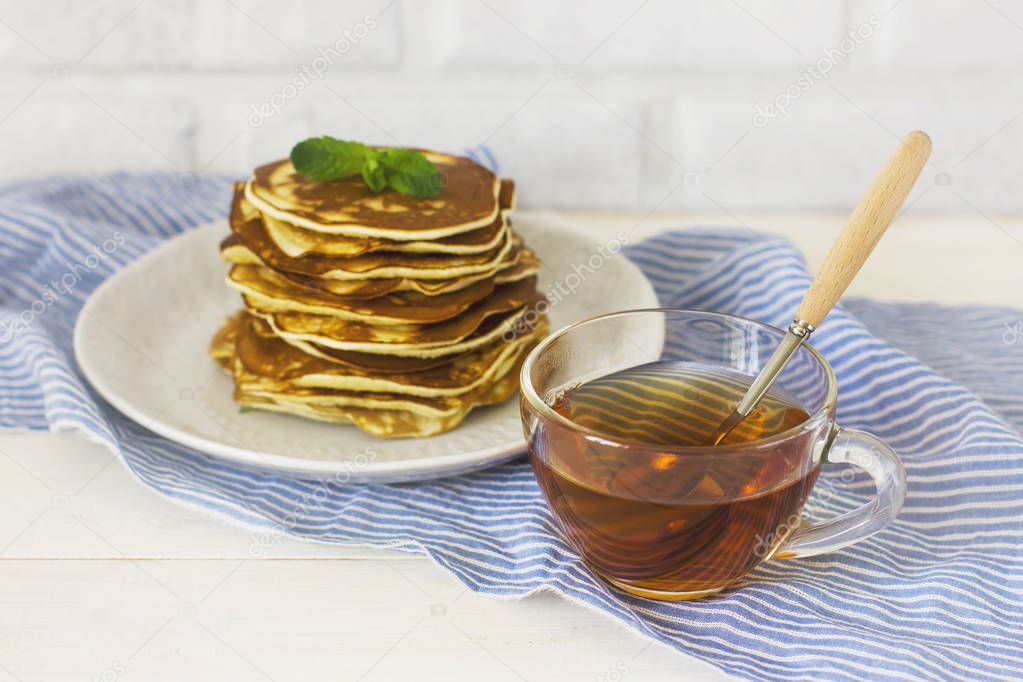 fresh baked pancakes with mint in white plate and cup of tea 