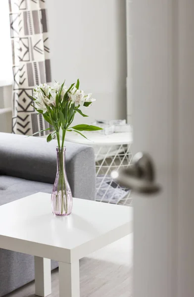 Porta aberta para quarto com buquê de flores na mesa, interior escandinavo — Fotografia de Stock