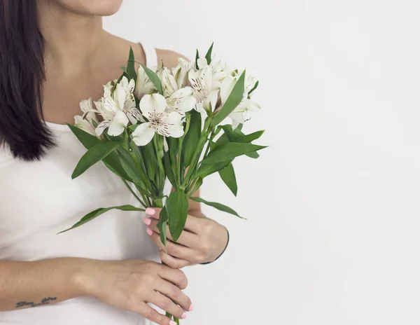 Kytice z bílých květů kosatců v rukou dívka s tmavými vlasy na bílém pozadí — Stock fotografie