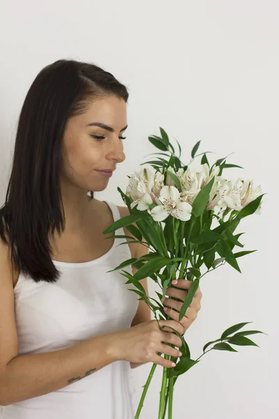 魅力的な若い女性は笑みを浮かべて白い背景に白い花アルストロメリアの花束を作成します。 — ストック写真