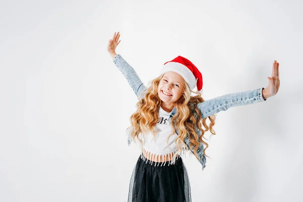 Feliz vestido a la moda pelo rizado entre chica en sombrero de santa, chaqueta de mezclilla y falda de tutú negro sobre fondo blanco — Foto de Stock