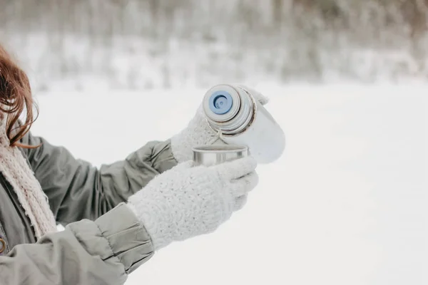 Γυναίκα με γάντια ρίχνει ζεστό τσάι από θερμός στο δάσος του χειμώνα — Φωτογραφία Αρχείου
