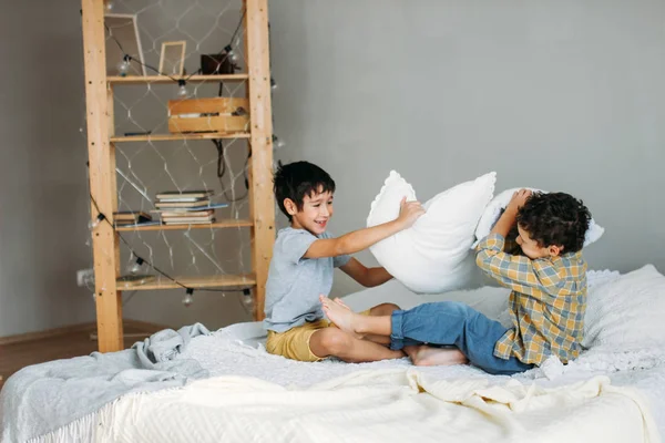 Lindos chicos adolescentes jugando con almohada en la cama de los padres en casa — Foto de Stock