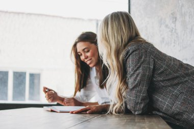 Young successful women colleagues discuss joint project, coachin