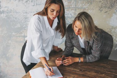 Young successful women colleagues discuss joint project, coachin