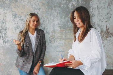 Young successful women colleagues discuss joint project, coachin