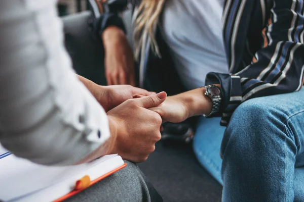 Kadın desteği ve yardım konsepti. Kadınlar modern çatı katında otururken birbirlerinin ellerini tutarlar. Ofis kadını desteği ve yardım konsepti. Modern çatı katında kadınlar el ele tutuşur.