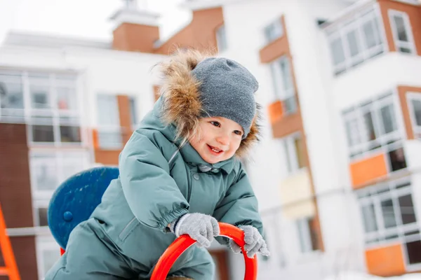 Roztomilý šťastný chlapeček v teplé celkově a šedý pletený klobouk v zimní ulici — Stock fotografie